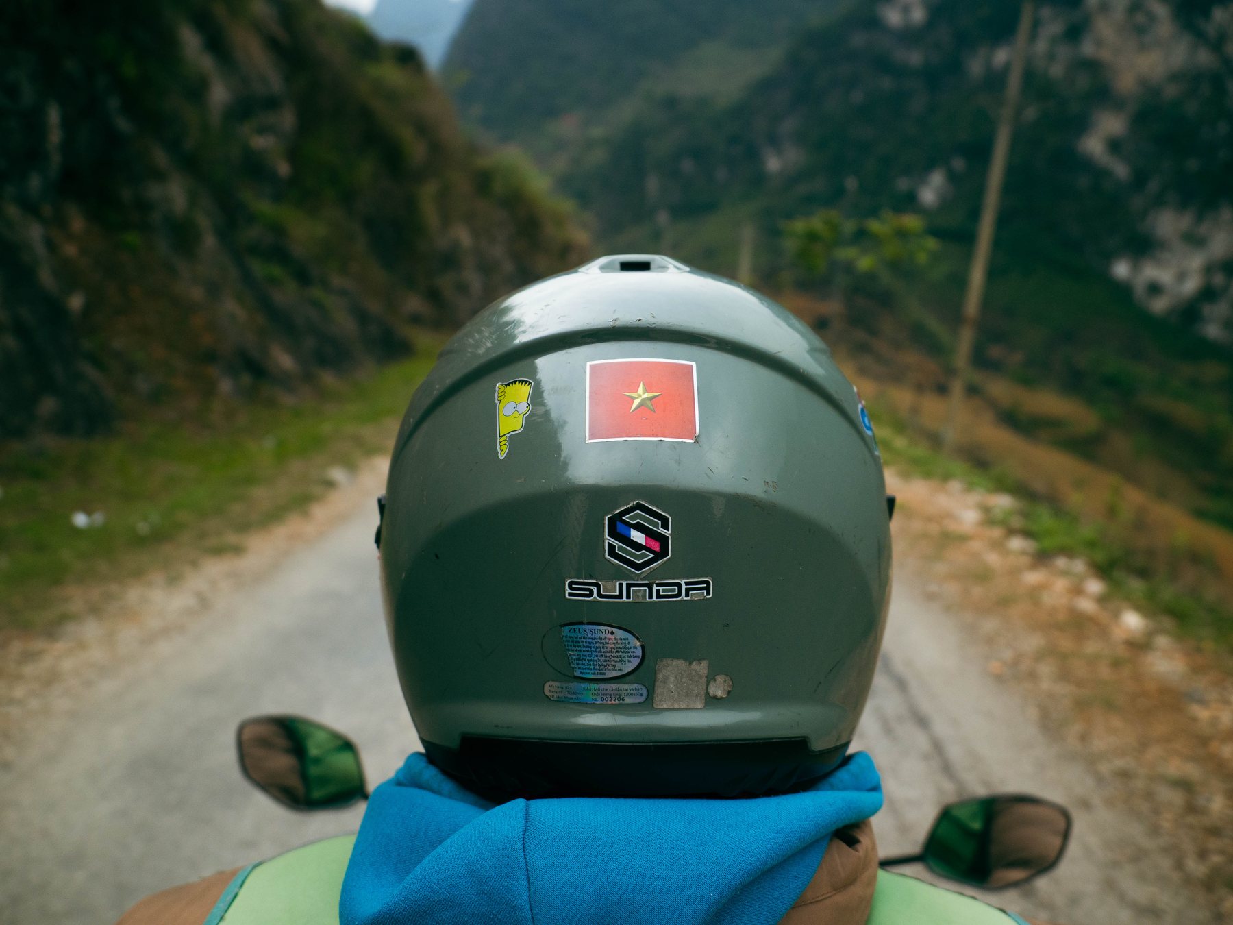 View over a green motorcycle helmet onto a mountain road