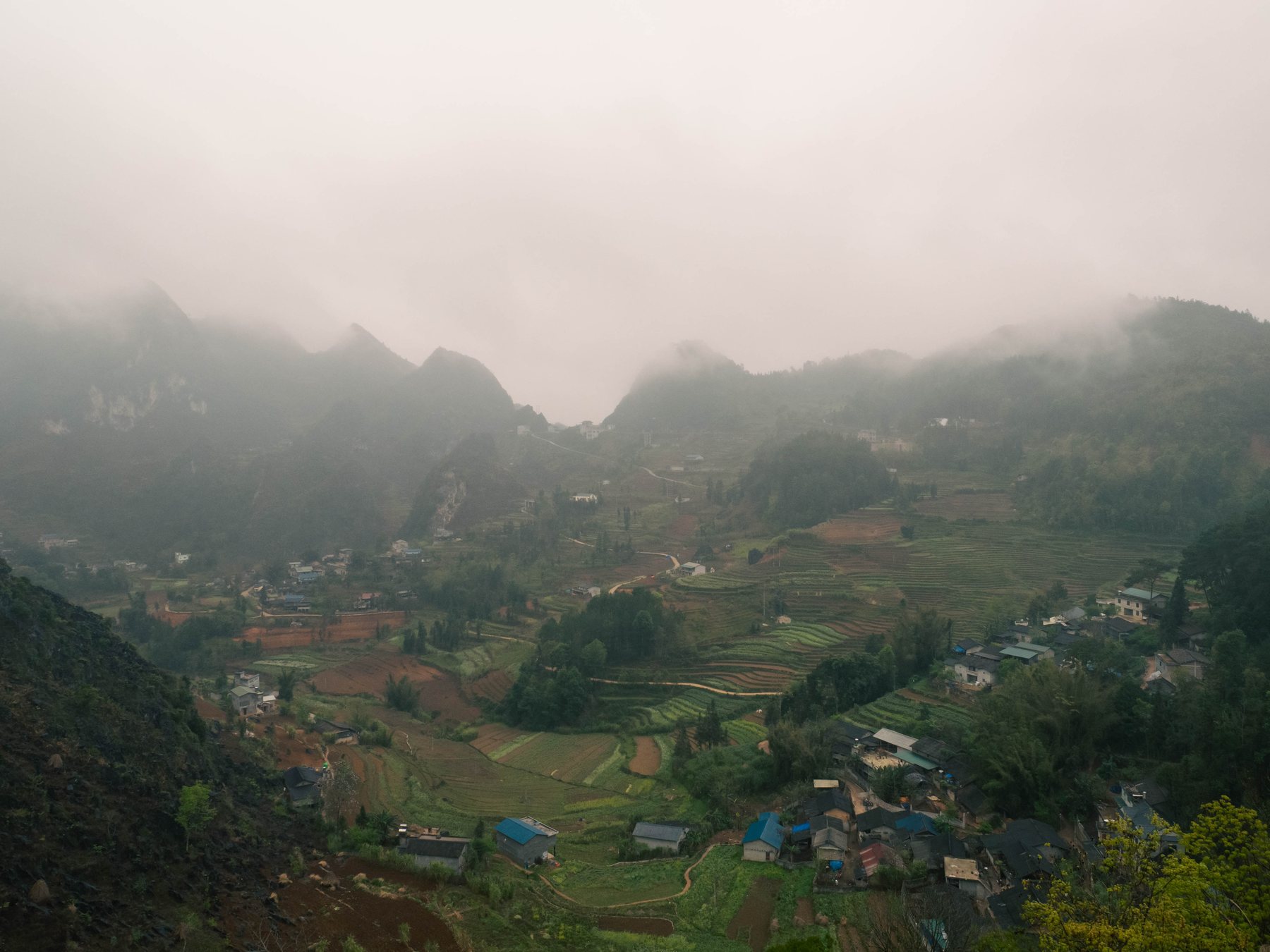 Village and terraced fields in a valley, wrapped in low cloud